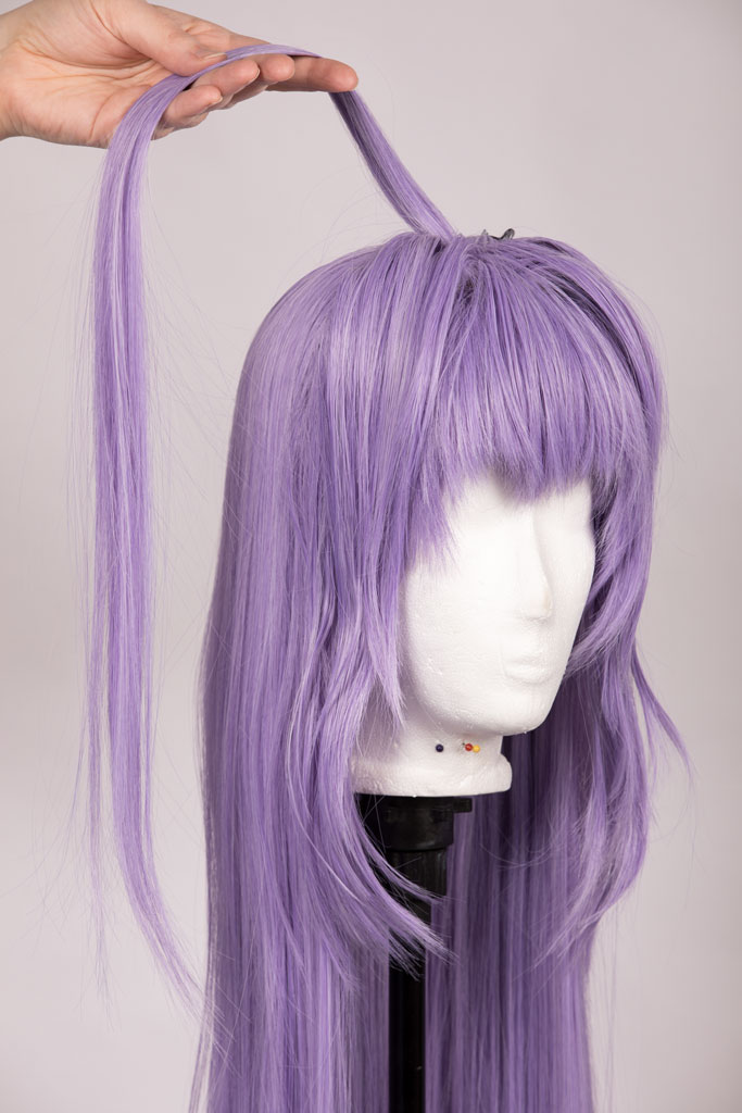lilac wig and a hand holding a single long strand of hair