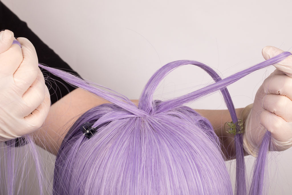 wig with a curved strand of hair and hands pulling two strands of hair apart