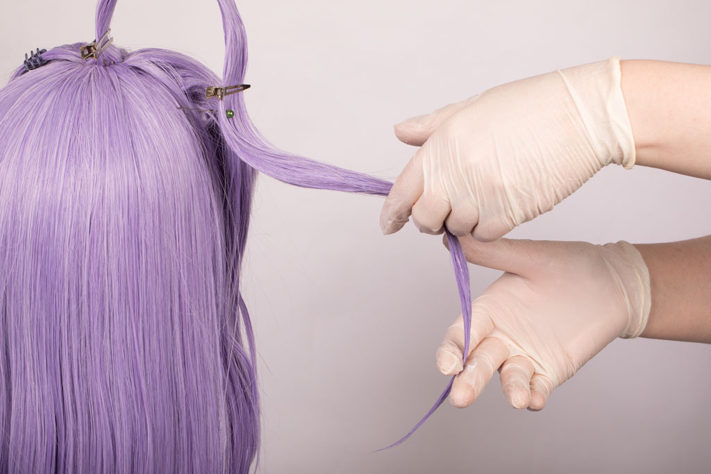 hands applying styling product to a long strand of hair