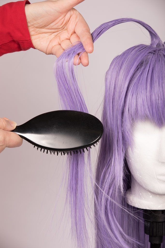hands brushing a strand of hair on a wig
