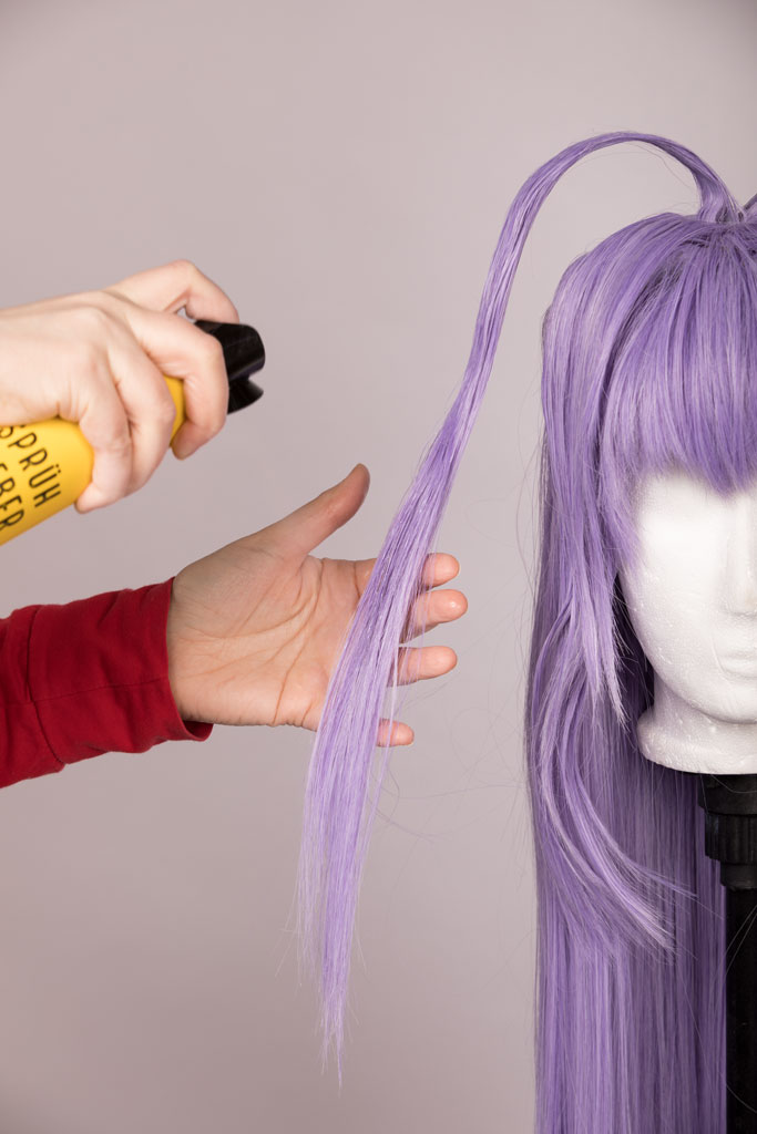 hands spraying hairspray on a wig