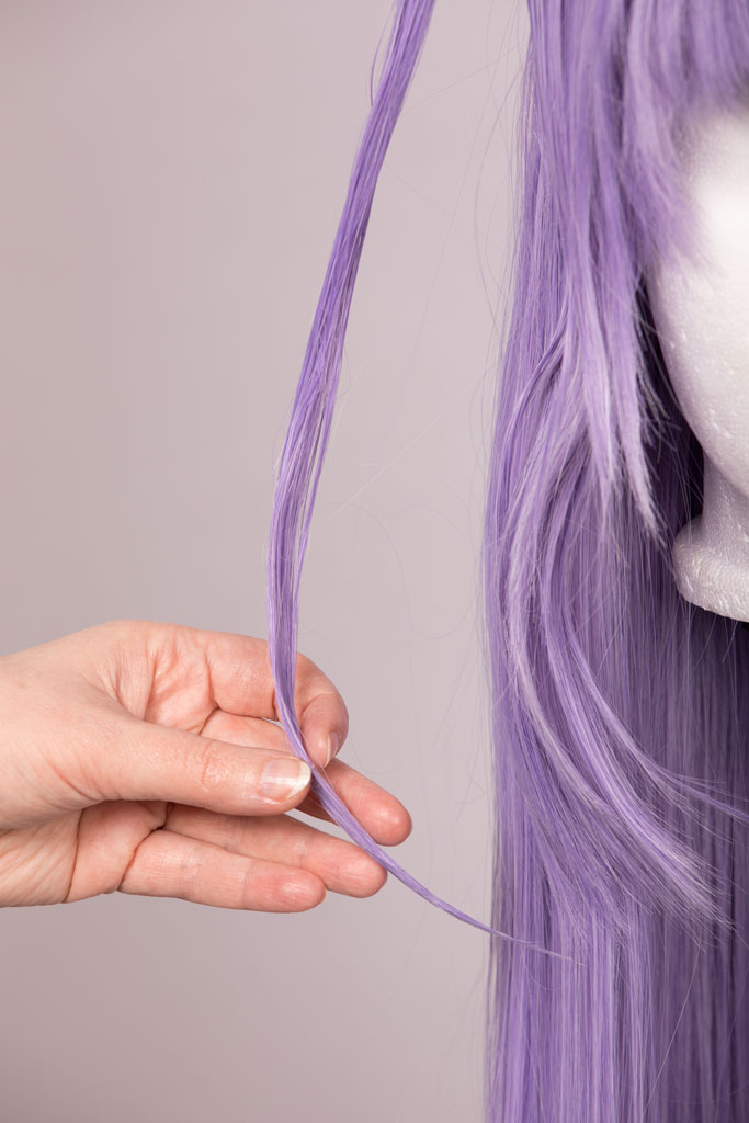 hands holding a strand of hair on a wig
