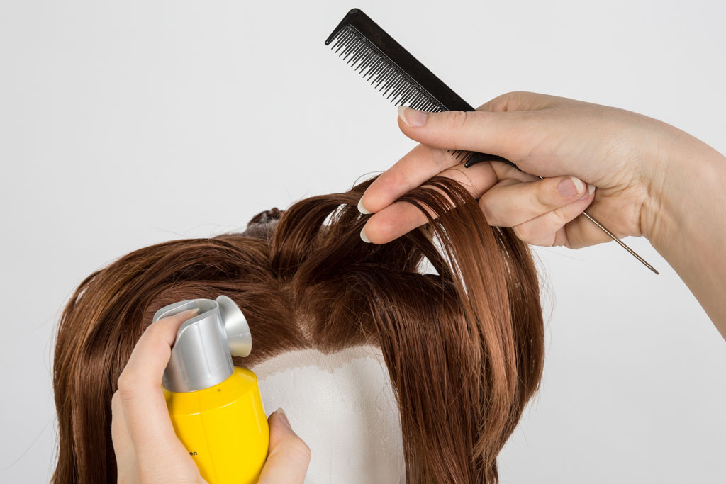 wig styling with a tail comb and hairspray